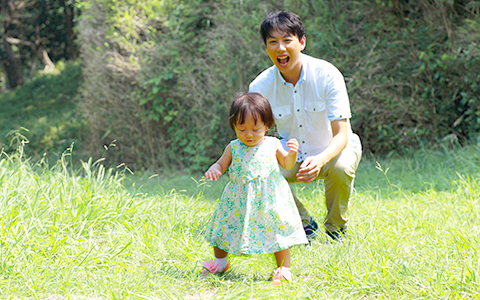 ファーストシューズを履いて歩く女の子とそれを見守る父親